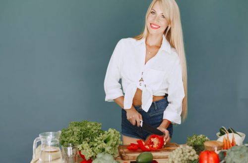 A smiling blonde woman chops vegetables, promoting healthy eating and lifestyle.